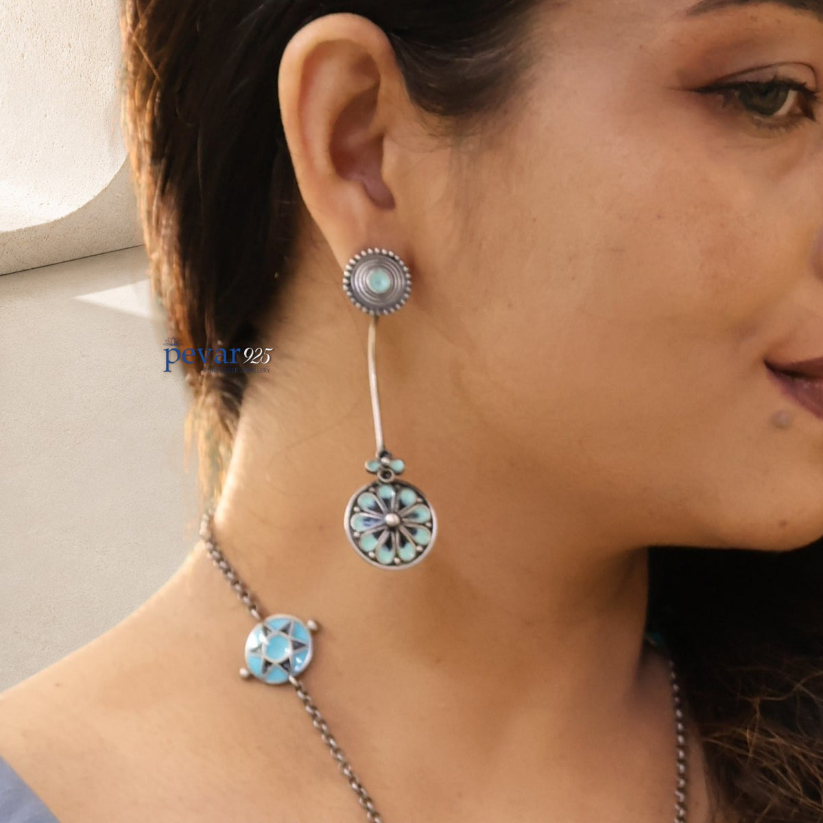 A woman wearing pevar925 oxidized silver turquoise minakari earrings and a matching floral enamel necklace.