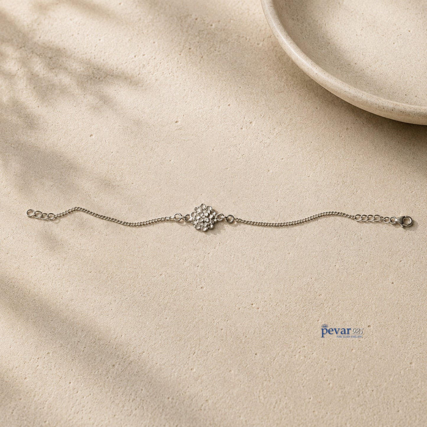 pevar925 sterling silver radiant blossom bracelet with a delicate flower charm on a fine chain, set on a neutral base.