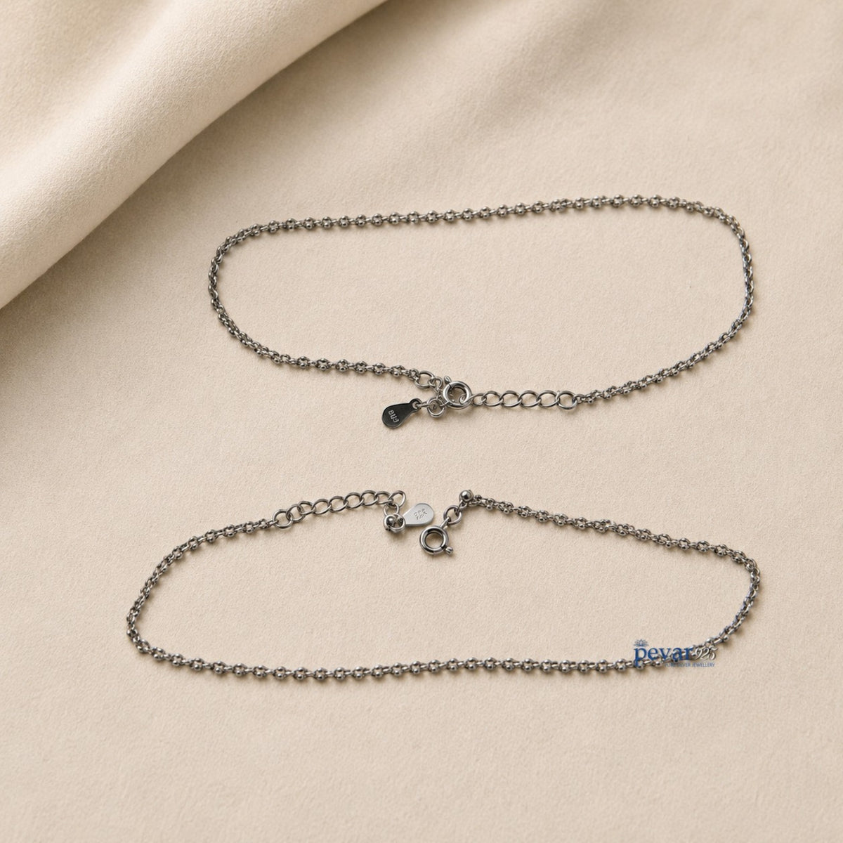 Two pevar925 sterling silver chain anklets with lobster clasps and adjustable extensions on a beige fabric background.