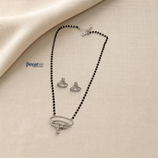 pevar925 sterling silver mangalsutra set with dual oval stone pendant, black beads, and matching earrings on fabric.