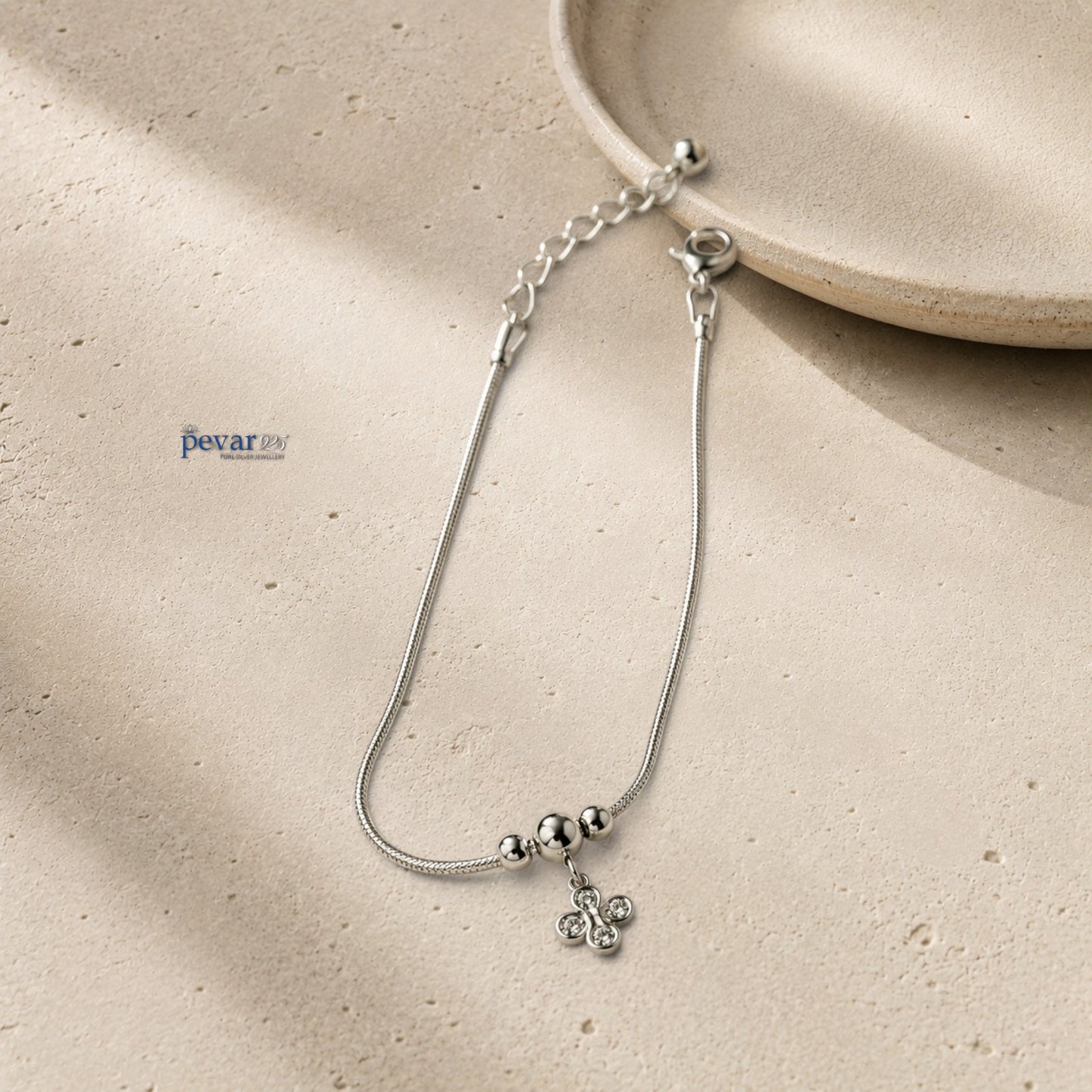 pevar925 sterling silver floral charm bracelet with a delicate chain, four-petal flower charm, and clear gemstones.