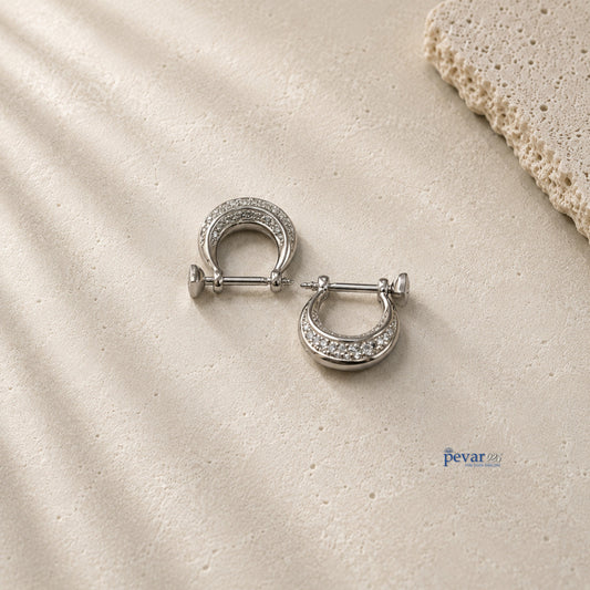 pevar925 sterling silver hoop earrings with rhodium plating and sparkling stones on a textured beige surface