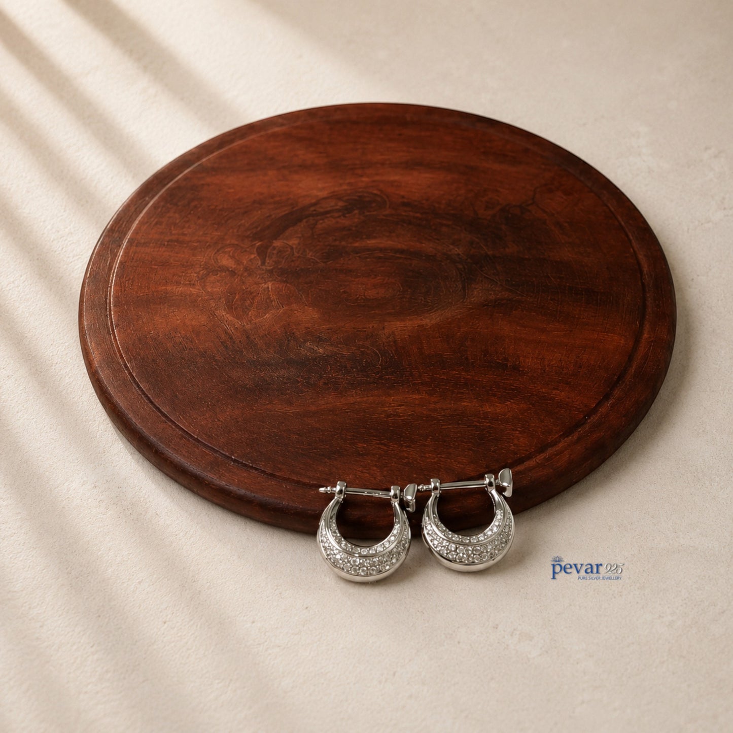 pevar925 unisex sterling silver hoop earrings with rhodium plating displayed on a dark wooden circular board