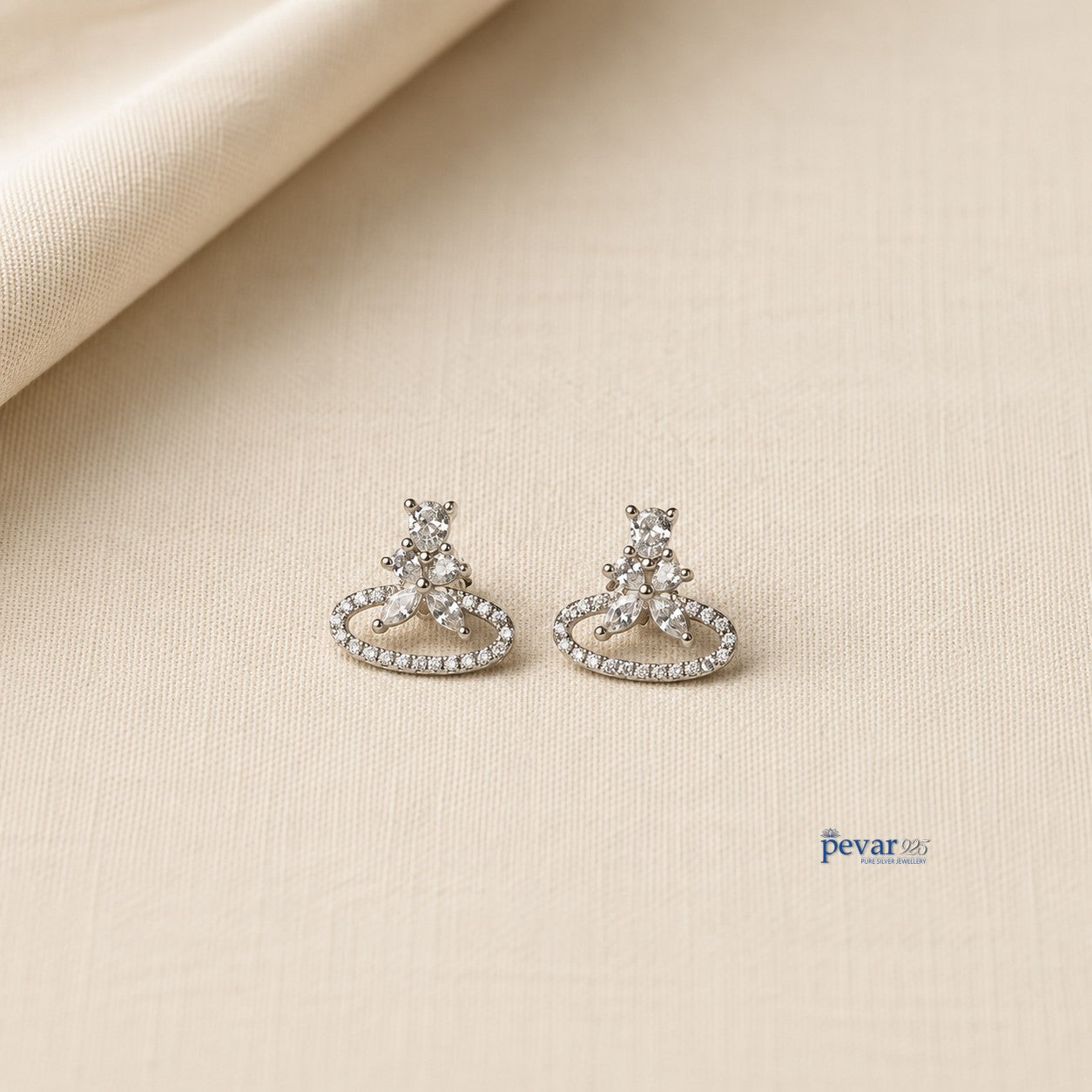 pevar925 sterling silver oval stud earrings with sparkling stones and rhodium plating on a textured beige background