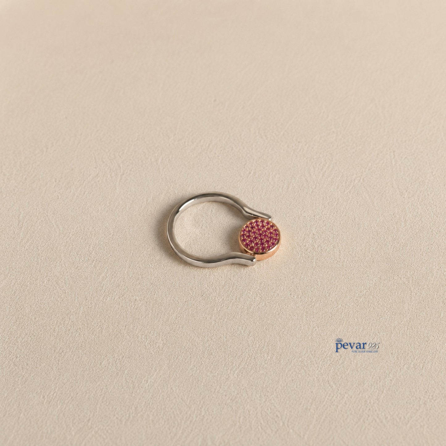 pevar925 sterling silver flip ring with a circular top featuring vibrant pink gemstones on a textured beige surface.