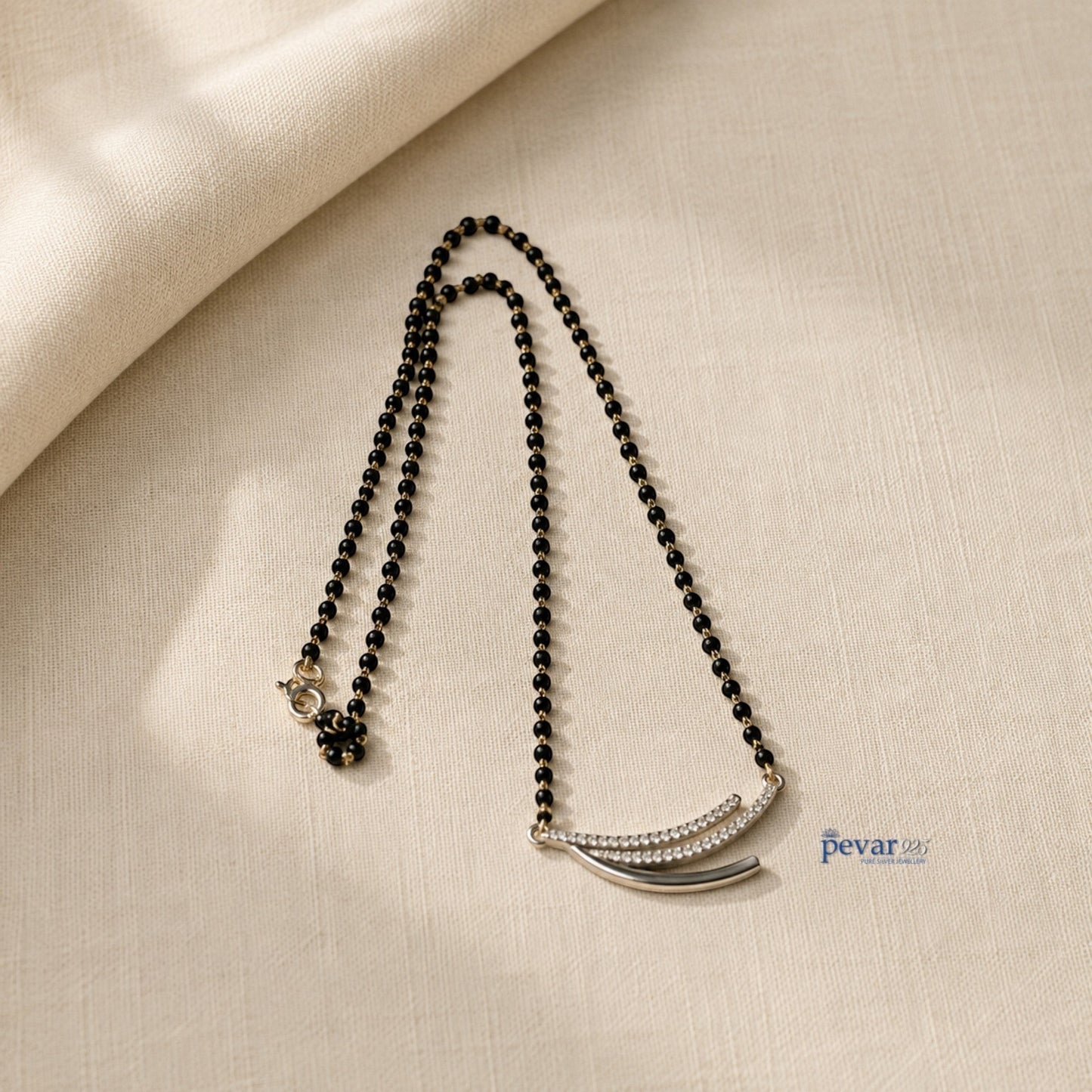 pevar925 sterling silver triple layer mangalsutra with black beads and a rhodium-plated curved motif on beige fabric