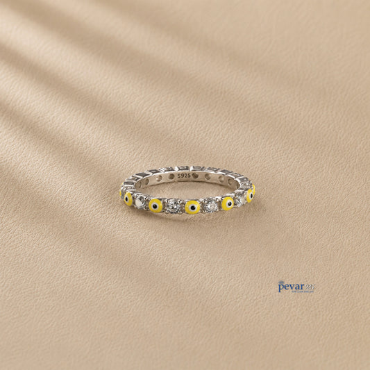 pevar925 sterling silver band ring featuring alternating yellow evil eye motifs and clear stones on a beige background