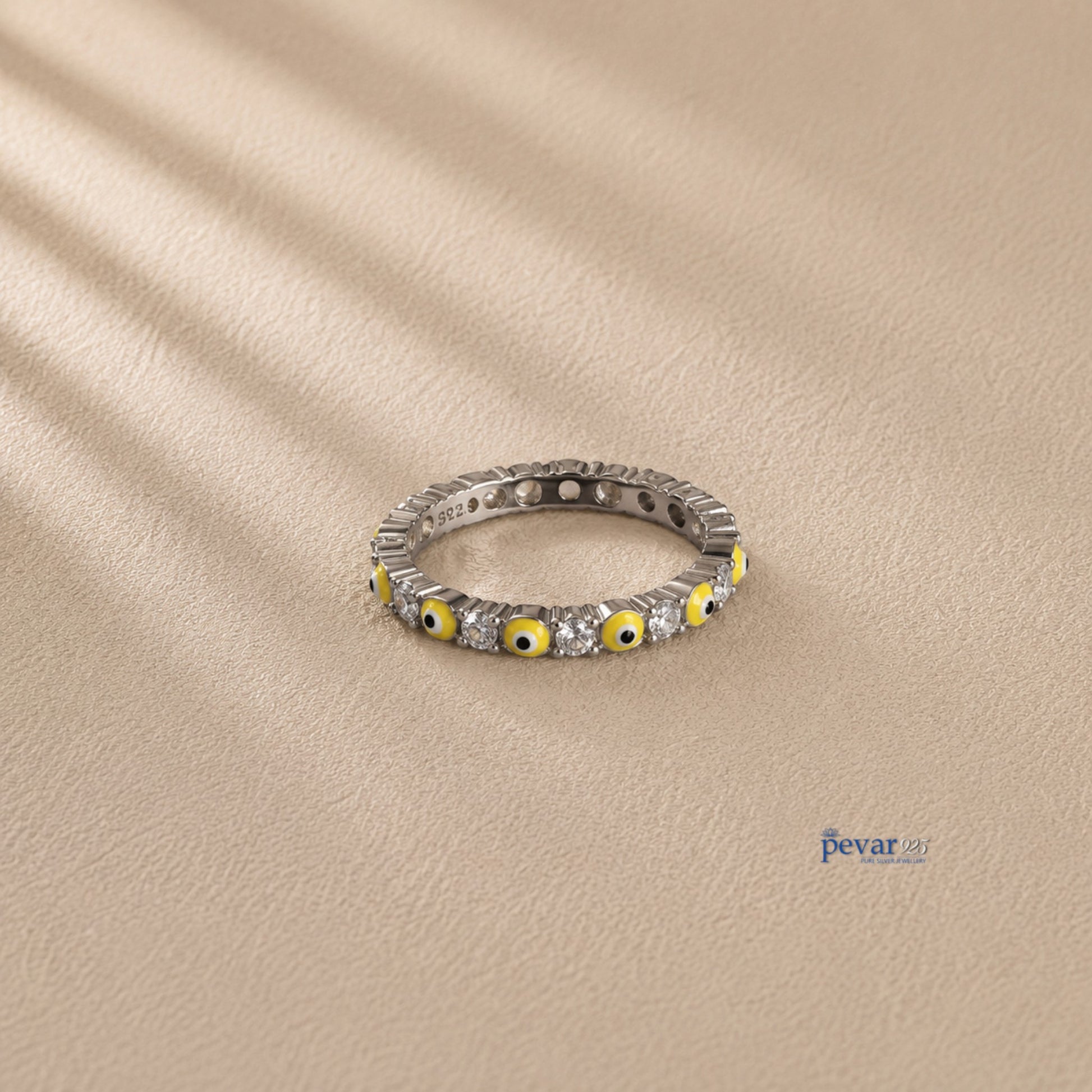 pevar925 sterling silver band ring featuring alternating yellow evil eye motifs and clear stones on a neutral background